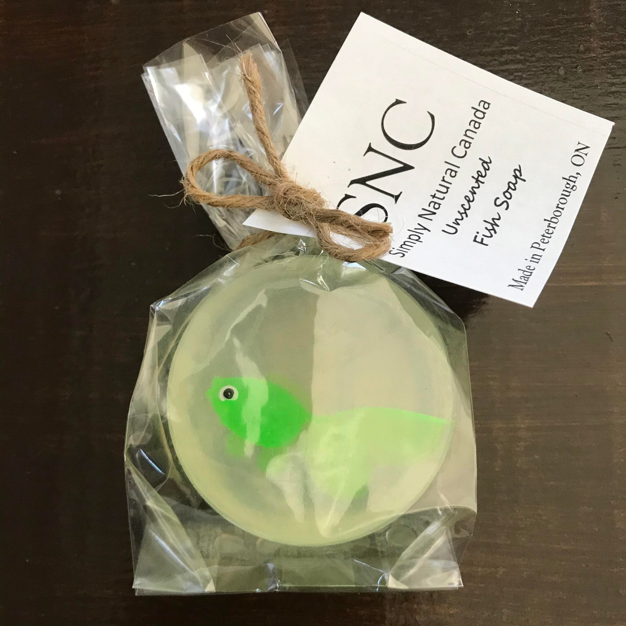 Green vinyl fish inside a clear round vegetable glycerin soap packaged inside a compostable bag and made in Canada by Simply Natural Canada