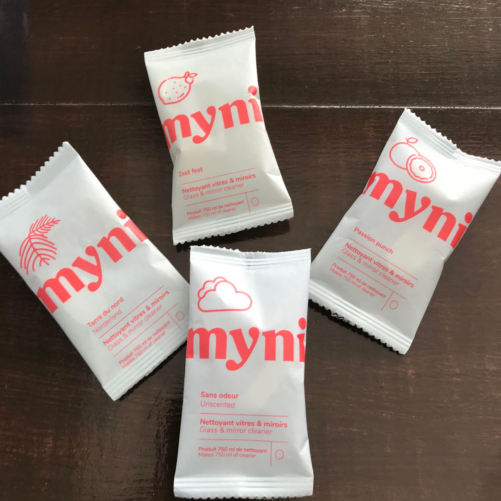 Glass and mirror cleaner concentrate tablets in compostable pouches made in canada by myni in unscented as well as Norderland (black spruce scent), Zest Fest (lemon mint scent) and Passion Punch (grapefruit and mango scent)