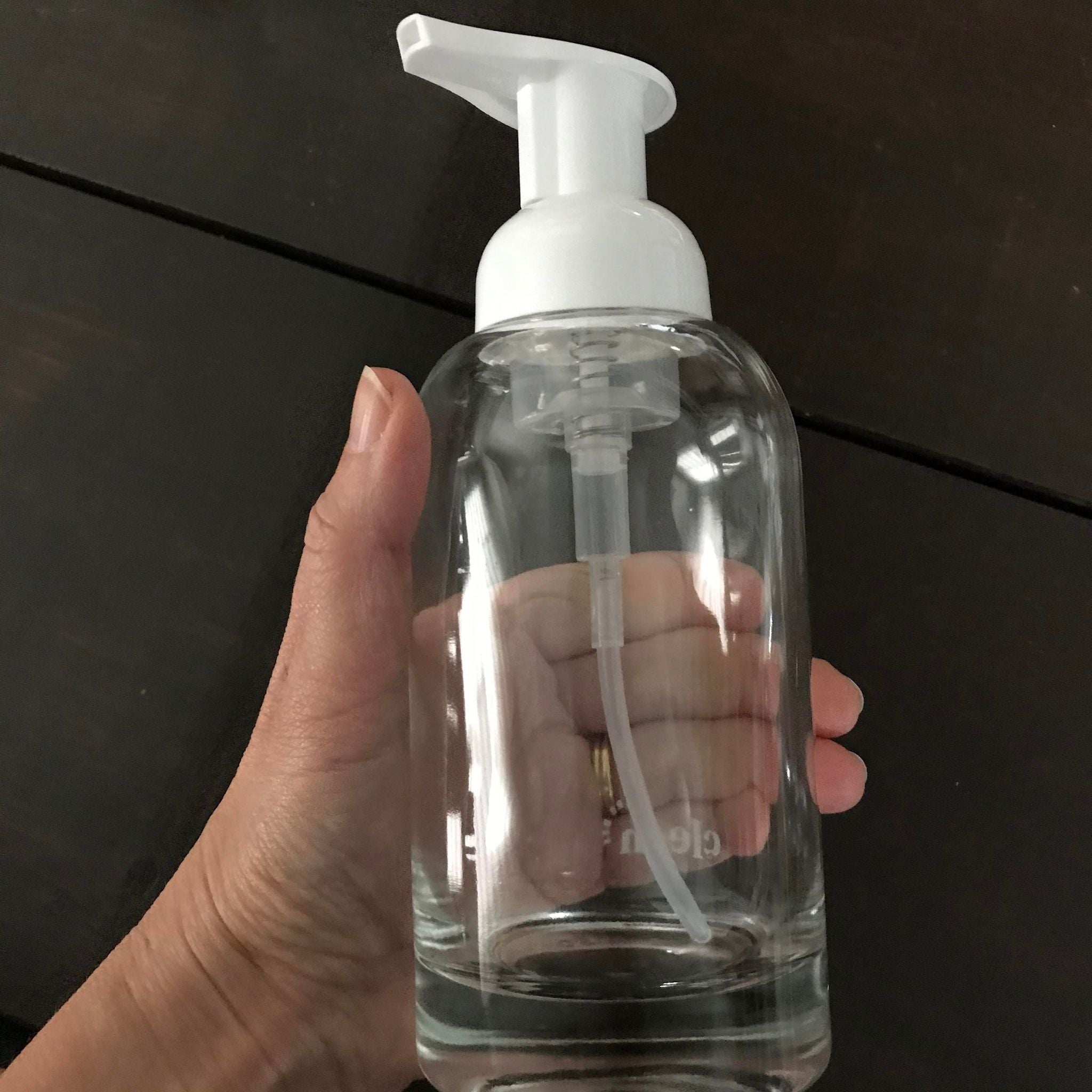 refillable clear glass hand soap foamer bottle with white pump top and white nature bee clean lettering at the bottom back of the reusable bottle