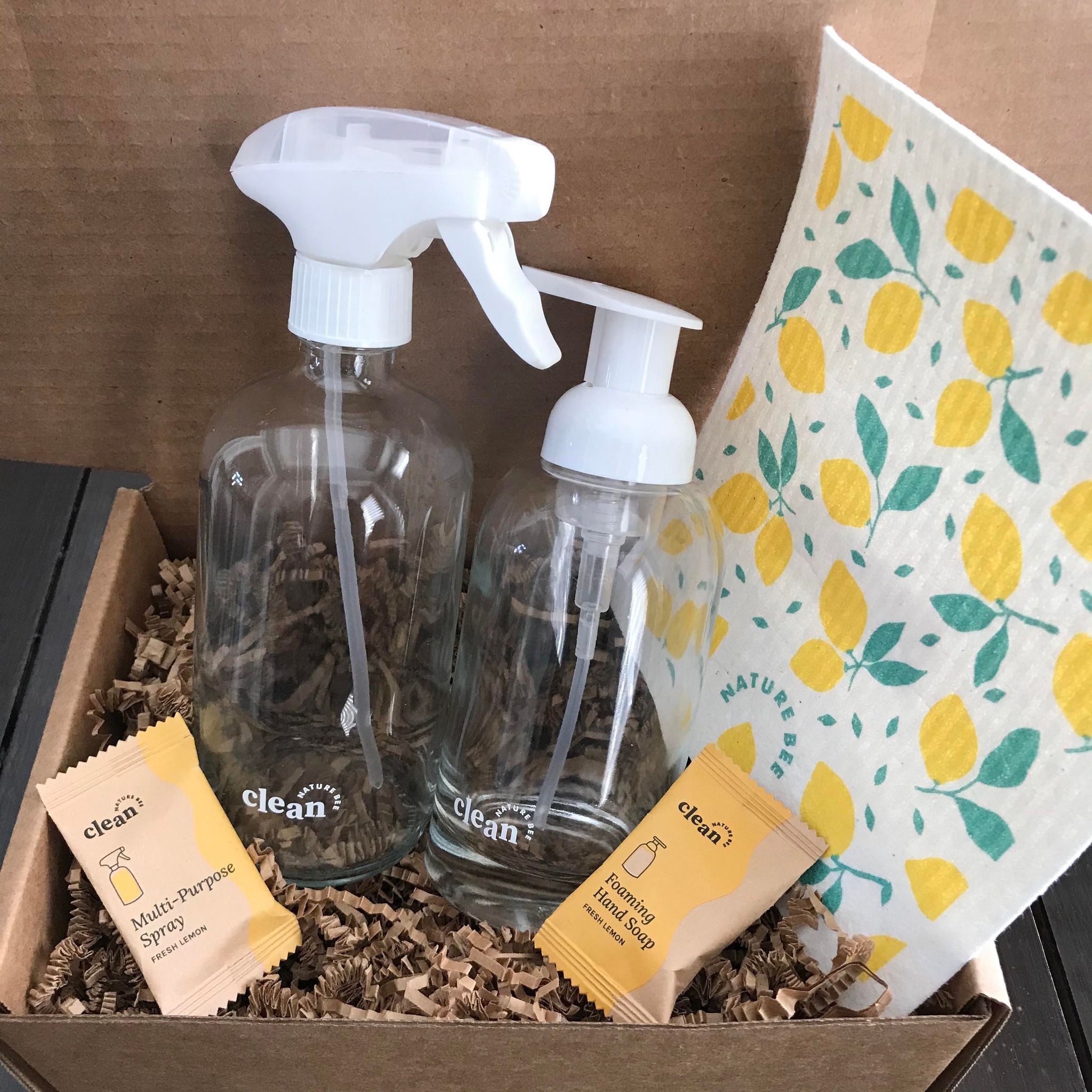 Fresh Lemon refill cleaning starter kit by the Canadian brand Nature Bee Clean comes in a box and includes a Swedish sponge cloth in a lemon pattern, 1 refillable clear glass foamer bottle with white pump top, 1 clear glass spray bottle with white sprayer and 2 tablets - 1 fresh lemon hand soap tablet and 1 fresh lemon multi-purpose spray cleaner tablet 