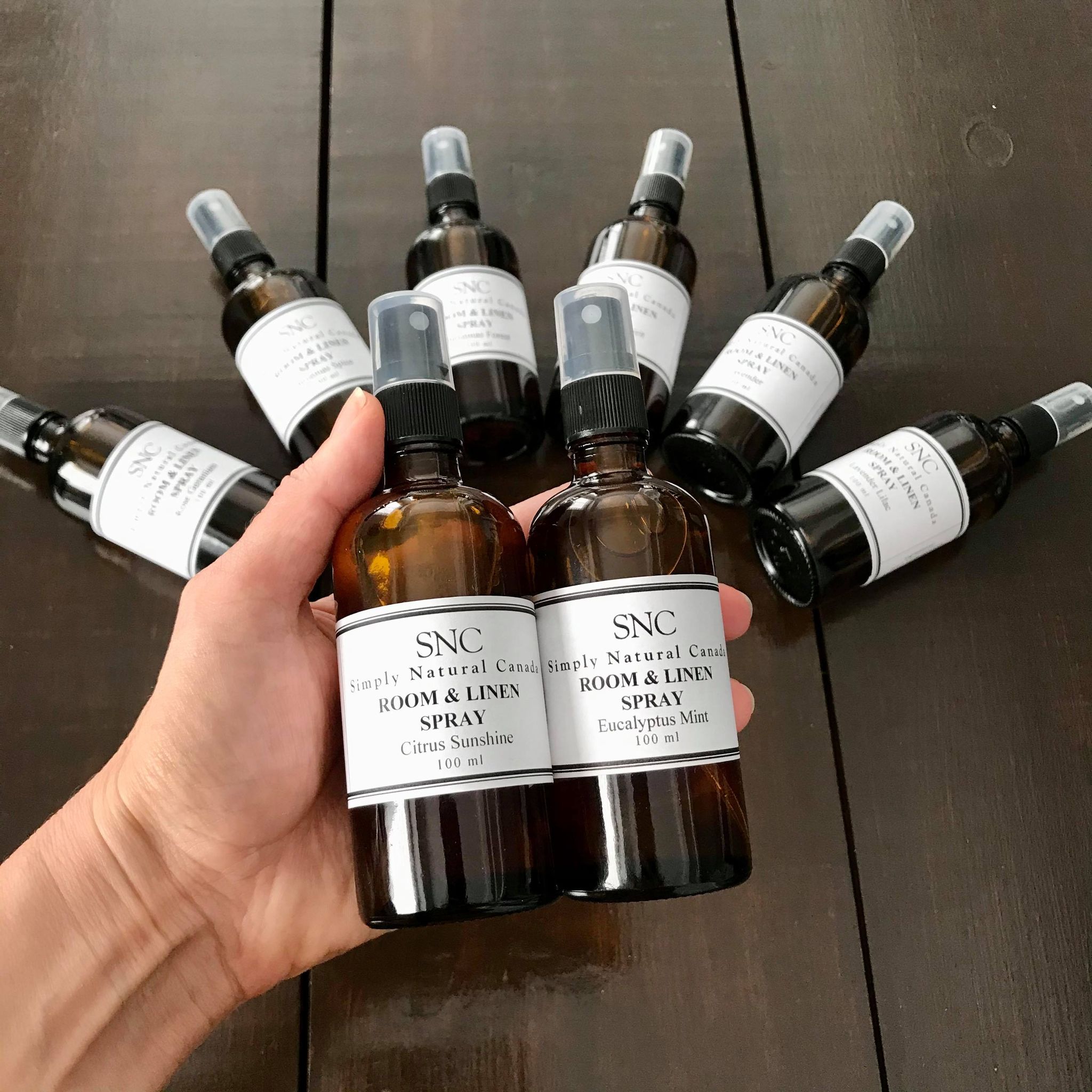 eight natural essential oil room and linen sprays in a 100 ml amber glass bottles with black spray tops with a black and white paper label made in canada by simply natural canada