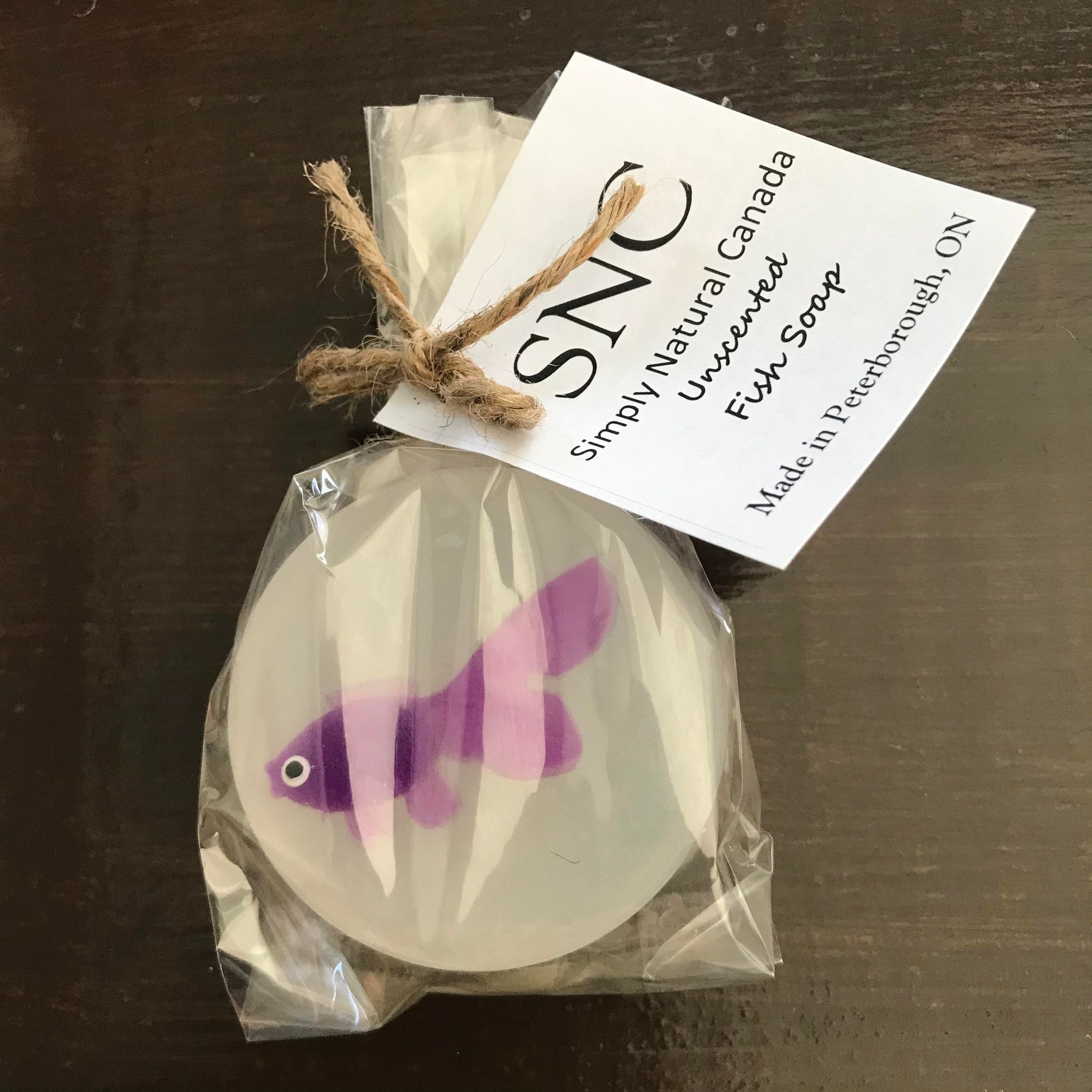 Purple vinyl fish inside a clear round vegetable glycerin soap packaged inside a compostable bag and made in Canada by Simply Natural Canada
