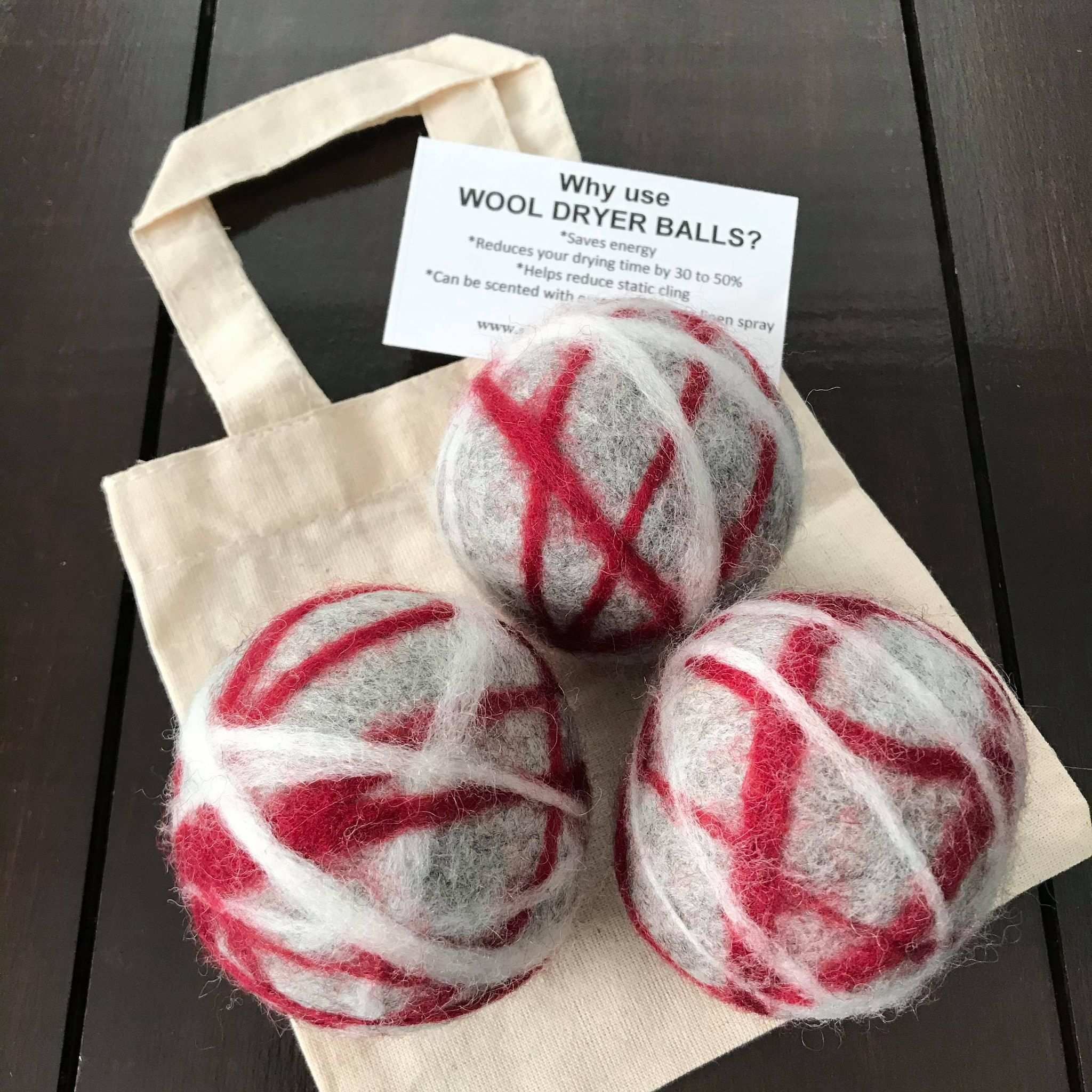 set of 3 canadian made grey, red and white 100 percent wool dryer balls sold in a cloth bag