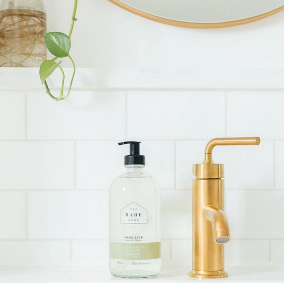 Canadian made  bergamot lime essential oil scented natural hand soap by The Bare Home sits beside a sink with a shiny faucet